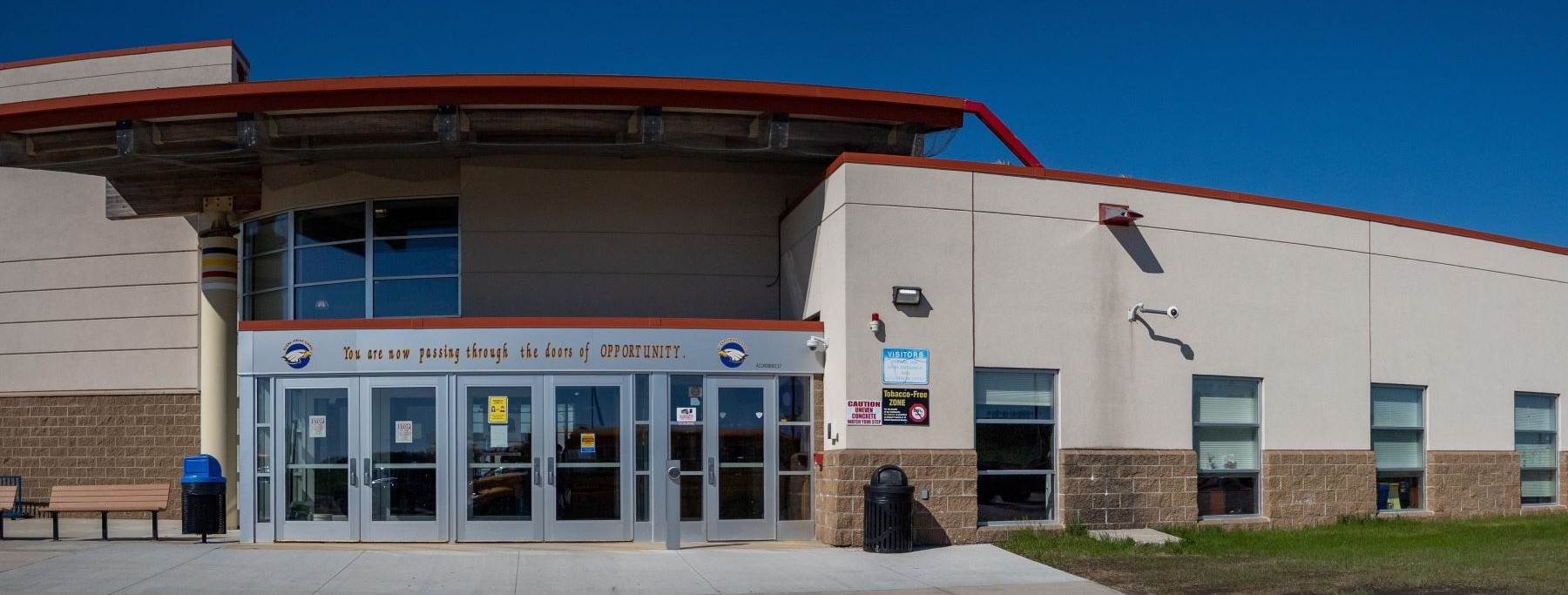 The front entrance of the Ojibwa Indian School building, featuring modern architecture and welcoming front doors.